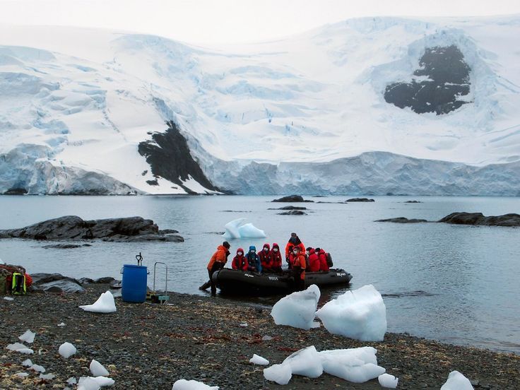 Orange Zodiac inflatable boat with expedition passengers approaching Antarctic shore